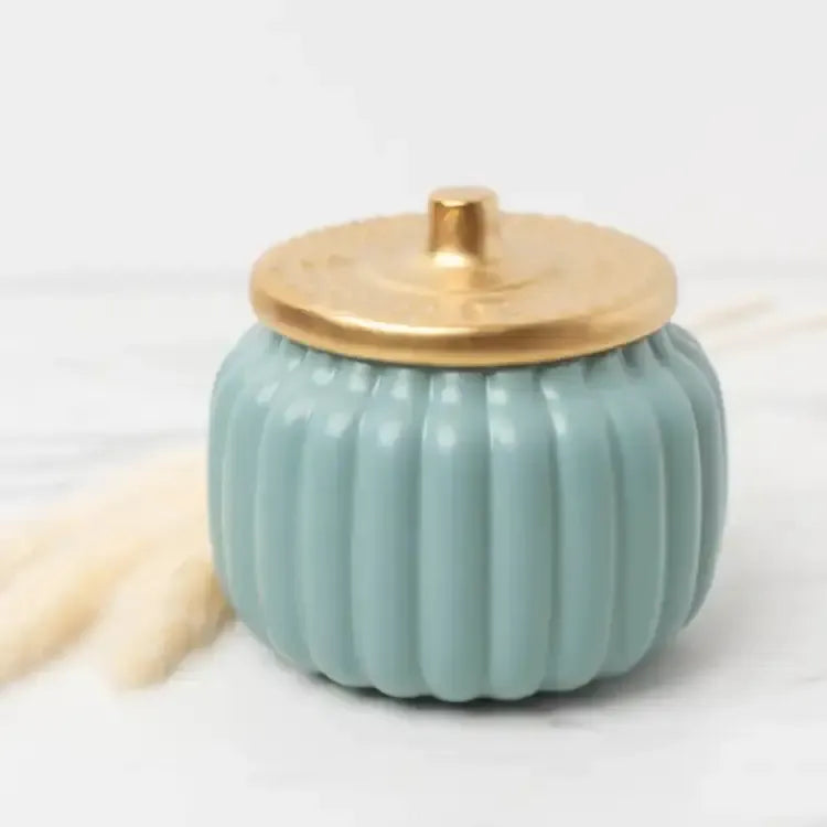 Hand-poured Homebody candle with warm amber, vanilla, and musk notes in blue pumpkin ceramic jar.
