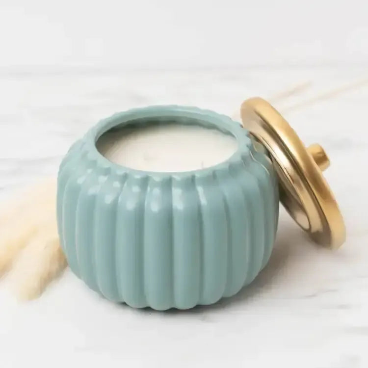 Homebody amber, vanilla, and musk candle with gold lid removed from pumpkin shaped jar.